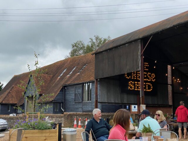 View of the farm buildings and the seating outside and inside at the cheese barn